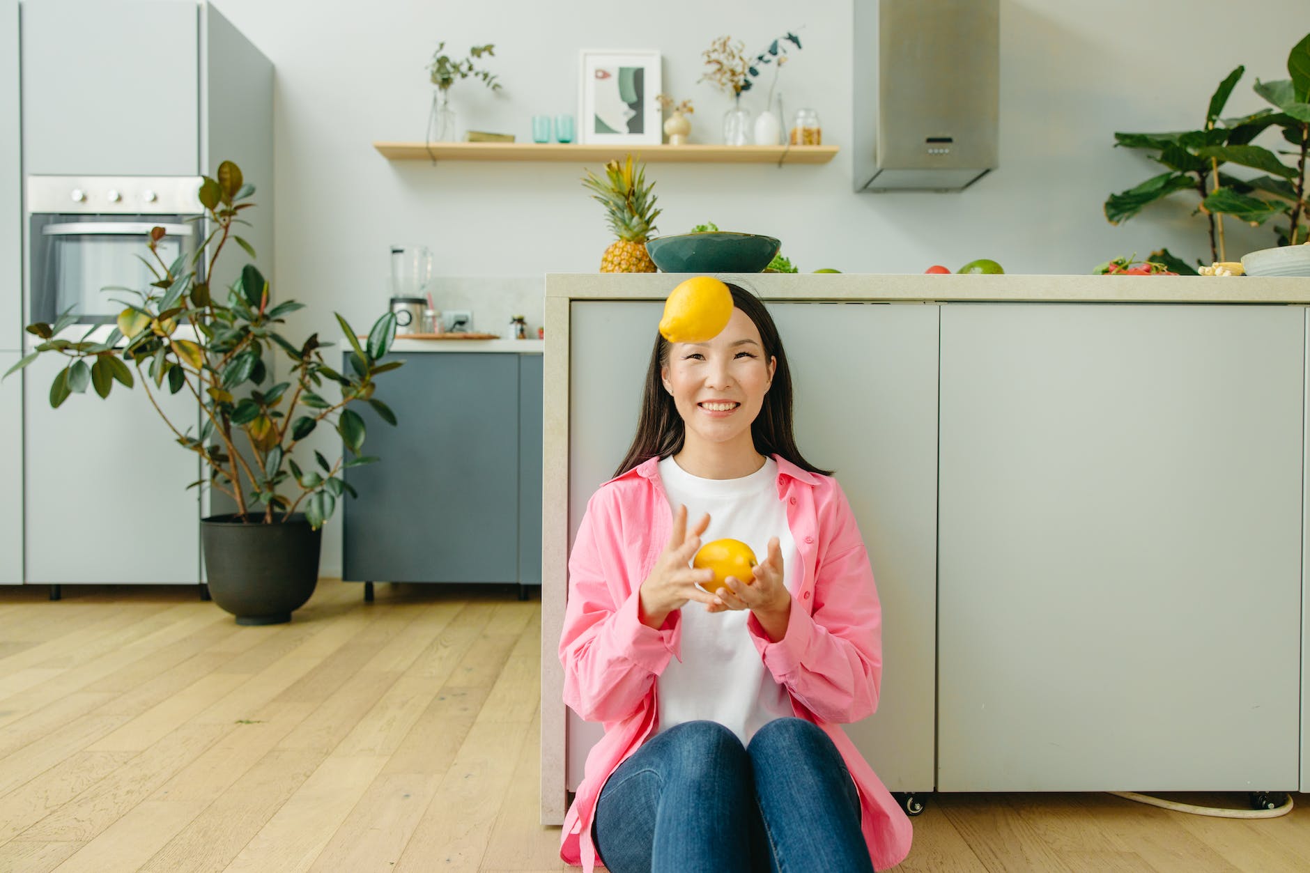 a woman sitting on the floor juggling the lemons she is holding
