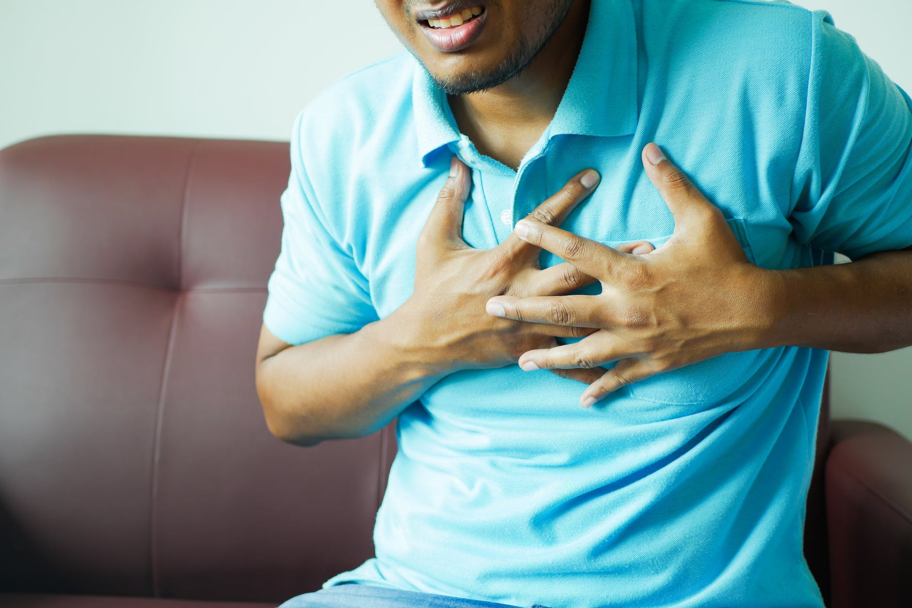 close up of a man in blue polo shirt with hands on chest